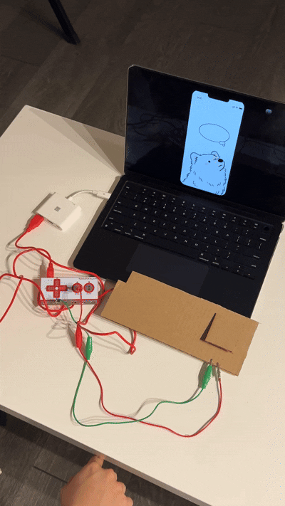 When the cardboard button is pressed, the copper tape triggers the MakeyMakey to send a “W” key signal, which ProtoPie uses to make the hungry bubble appear and play the eating sound. This final setup shows the complete flow from a real physical press to the dog’s digital response, making the interaction feel instant and real.